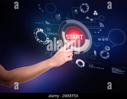 Man pointing at start icon on dark background, closeup Stock Photo
