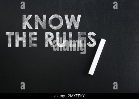 Phrase Know the rules and piece of chalk on blackboard, top view Stock Photo