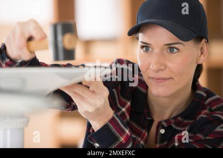 concentrated female worker using a hammer Stock Photo