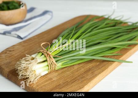 Fresh green spring onions on wooden board, closeup Stock Photo