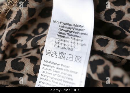 Clothing label with care symbols and material content on polyester shirt, closeup view. Wash with similar colors Stock Photo
