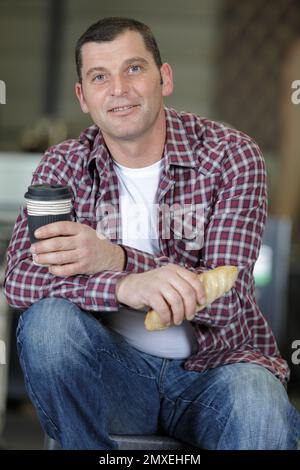 worker drinking coffee and resting sitting in factory Stock Photo