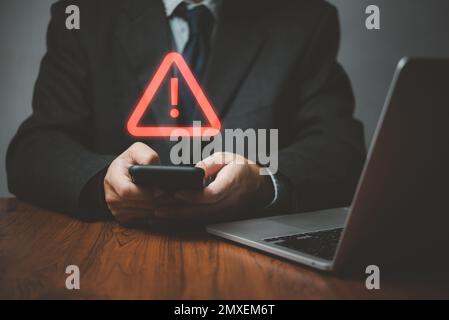 Businessman programmer, developer using smartphone with triangle caution warning sign for notification error and maintenance concept. Stock Photo