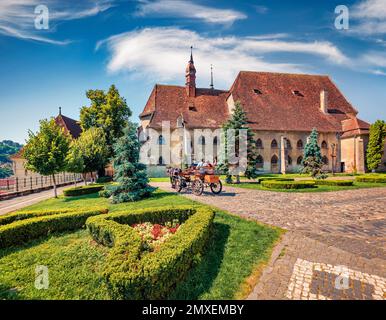 Traveling in a horse-drawn carriag in Sighisoara town. Wonderful summer view of Evangelical Church. Sunny morning scene of medieval town of Transylvan Stock Photo