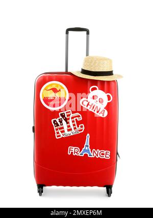 Modern suitcase with travel stickers and hat on white background Stock Photo