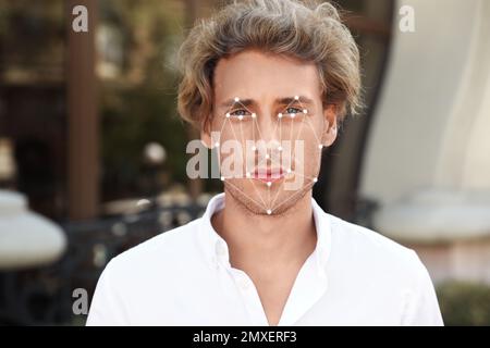 Facial recognition system. Young man with digital biometric grid, outdoors Stock Photo