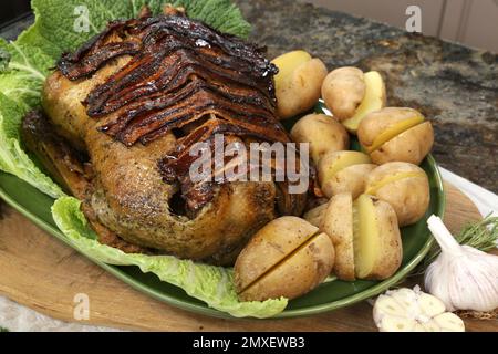 Goose stuffed and roasted covered with bacon served with baked potatoes. Stock Photo