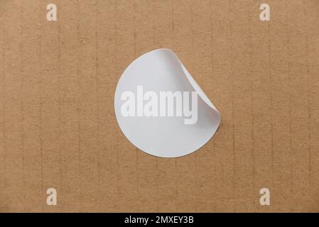 Blank white round stickers with folded corner on cardboard background. Stock Photo