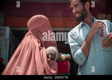 A woman wearing a burqa with a child on her arms and an adult man, Swatt Valley, Pakistan Stock Photo