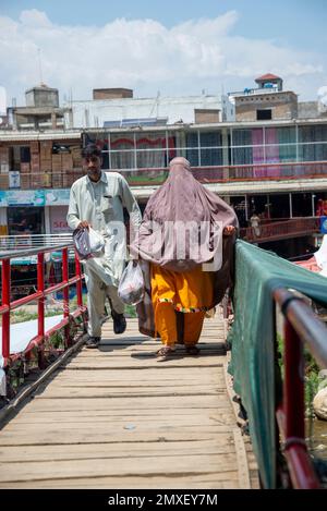 An adult man and a woman wearing a burqa on a bridge, Swatt Valley, Pakistan Stock Photo