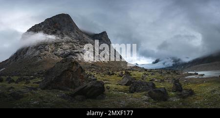 Southwest face of Mt. Thor, highest vertical cliff on Earth, on a cloudy September day. Hiking in wild, remote arctic valley of Akshayuk Pass, Baffin Stock Photo