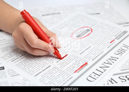 Woman marking advertisement in newspaper, closeup. Job search concept Stock Photo