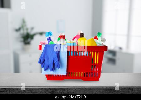 Basket with cleaning supplies on stone surface in modern room Stock Photo