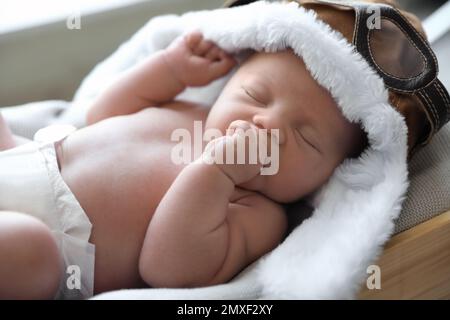 Cute newborn baby in aviator hat sleeping on blanket, closeup Stock Photo
