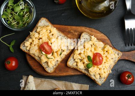 Tasty scrambled egg sandwiches served on black table, flat lay Stock Photo