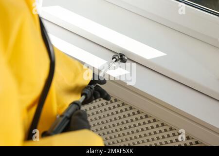 Pest control worker spraying pesticide on window sill indoors, closeup Stock Photo