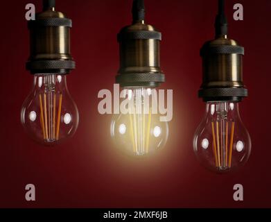 Idea concept. Glowing light bulb among others on red background Stock Photo