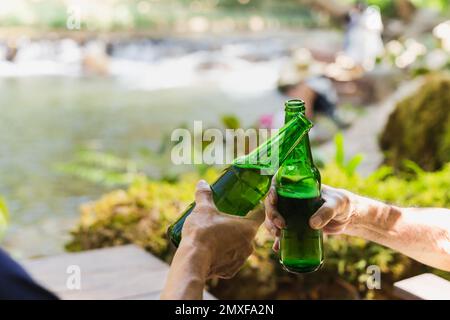Senior man toasting with bottle beer together with his son on vacation Stock Photo