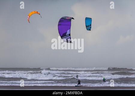 Bright Kites, Wind Surfers, Atlantic Waves, Reflections and a Dark Stormy Sky at Northam Beach, Devon (Landscape View) Stock Photo