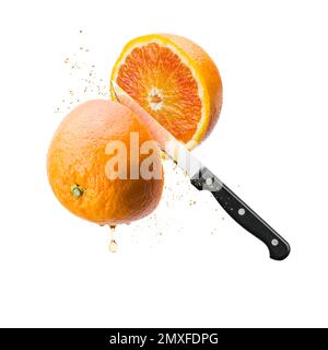 Sliced floating orange fruit with knife with juice drops, isolated on white background. Stock Photo