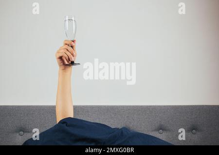 Champagne in a man's hand in bed. Hangover, alcohol intoxication concept. Holidays greetings Stock Photo