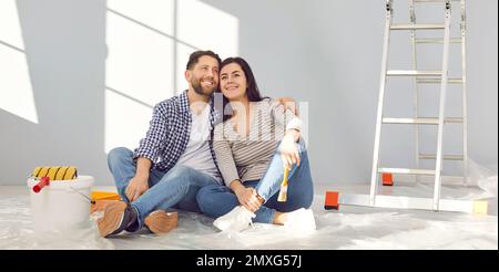 Happy young family couple relaxing on floor after doing renovations in their new house Stock Photo