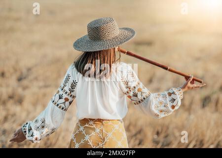 Rural woman plays on wooden flute - ukrainian telenka, tylynka in wheat field Stock Photo