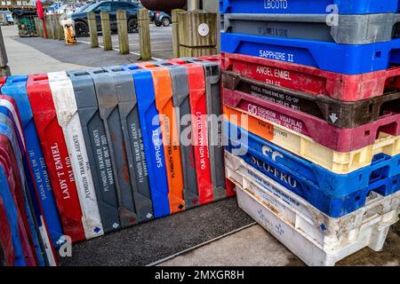 Plastic fish boxes, crates from many different ports in Europe stored on quayside. Colourful abstract, background, concept. UK fishing industry. Stock Photo