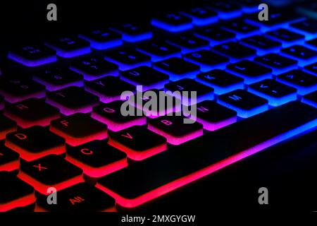 Fragment of the game keyboard with color backlight on black background. Close-up of computer keyboard. Selective focus. Stock Photo