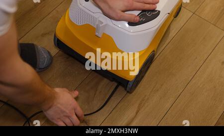 Caucasian man packing cable of the vacuum cleaner inside the storage in it and made it. Angry Man trying to pack sticked cable in vacuum cleaner. Stock Photo