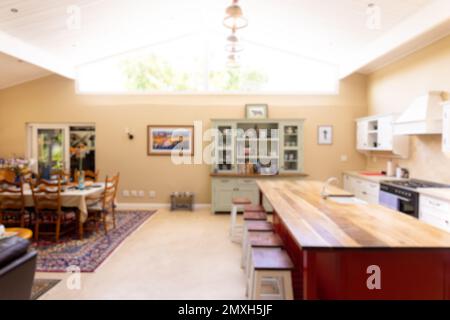 Illuminated lights hanging on ceiling over stools arranged by wooden kitchen island in kitchen Stock Photo