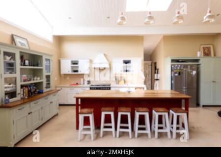 Pendant lights hanging on ceiling over wooden kitchen island and stools in modern kitchen Stock Photo