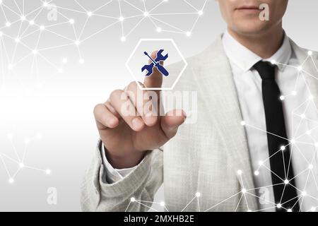 Man touching icon on virtual screen against light background, closeup. Technical support Stock Photo