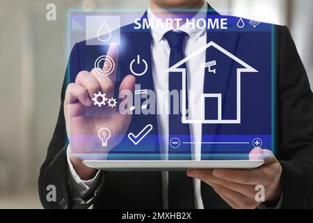 Woman using tablet to set indoor air humidity, closeup. Smart home automation system Stock Photo