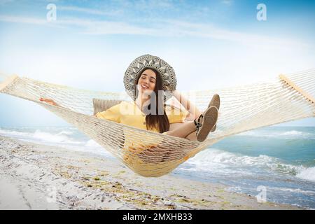 Woman resting in hammock near sea on sunny day Stock Photo
