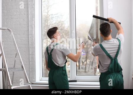 Professional workers tinting window with foil indoors Stock Photo