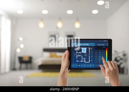 Woman using tablet to set indoor temperature, closeup. Smart home automation system Stock Photo