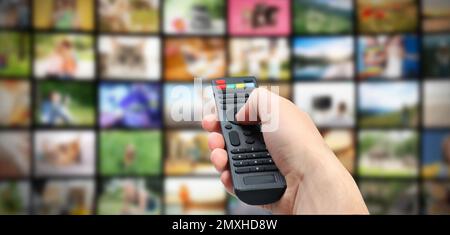 Streaming video services. Man using remote control to change channels on TV, closeup Stock Photo