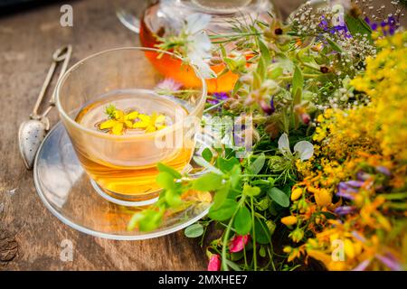 Summer healthy herbal tea in a glass teapot and bunches of medicinal herbs on wooden board. . Phytotherapy. Herbal medicine Stock Photo
