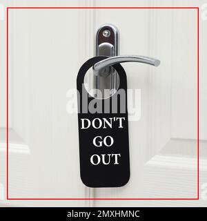 Closed door with sign DON'T GO OUT on handle. Stay at home during coronavirus quarantine Stock Photo