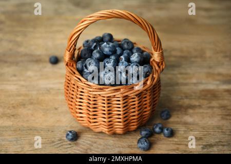 Tasty ripe blueberries in wicker basket on wooden table Stock Photo