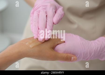 Woman getting wax epilation of hand in salon, closeup Stock Photo