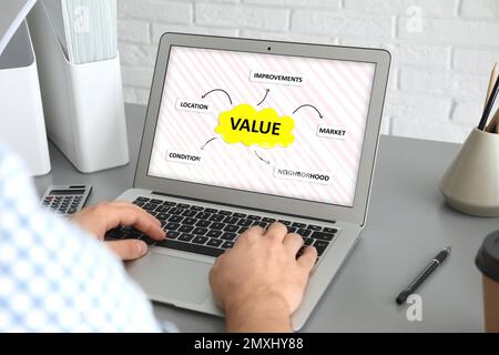 Property value concept. Man working with laptop at table indoors, closeup Stock Photo