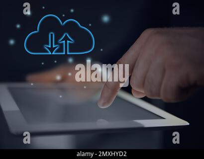 Cloud computing and storage concept. Man using tablet on dark background, closeup Stock Photo