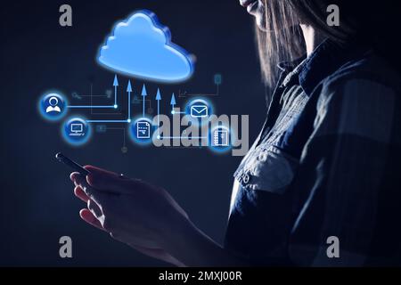 Cloud computing and storage concept. Woman using smartphone on dark background, closeup Stock Photo