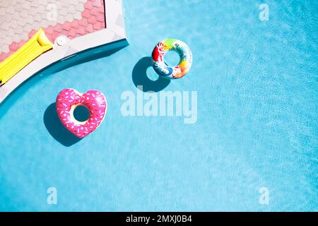 Inflatable rings floating in swimming pool, top view with space for text. Summer vacation Stock Photo