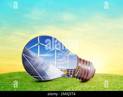 Alternative energy source. Light bulb with solar panels and wind turbines outdoors Stock Photo