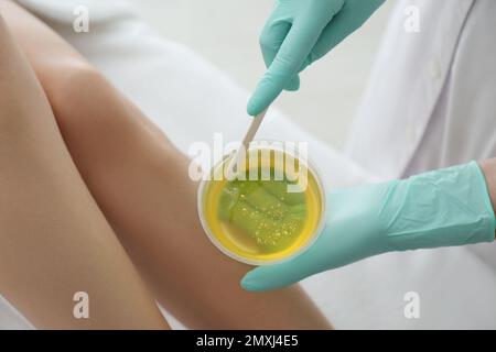 Woman getting wax epilation of legs in salon, closeup Stock Photo