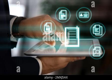 Man using tablet indoors and documents icons, closeup Stock Photo