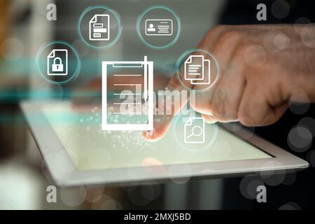 Man using tablet indoors and document icons, closeup Stock Photo